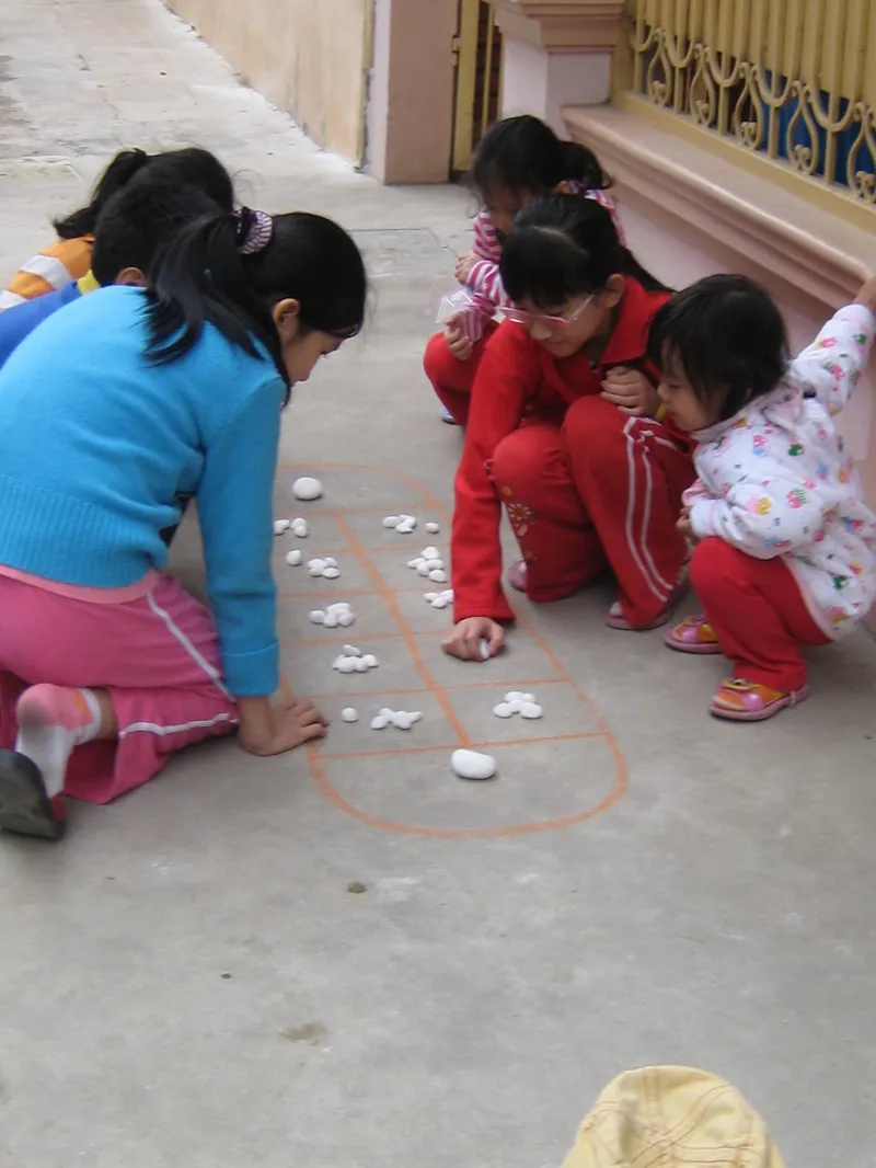 Bàn Ô Ăn Quan vẽ trên nền sân, với các quân nhỏ đặt trong ô.
