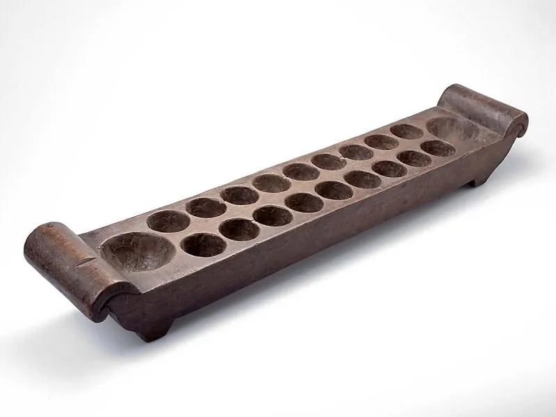 Hiện vật bàn Mancala/Dakon bằng gỗ với hai hàng chín hốc và hai kho; bộ sưu tập Wereldmuseum.