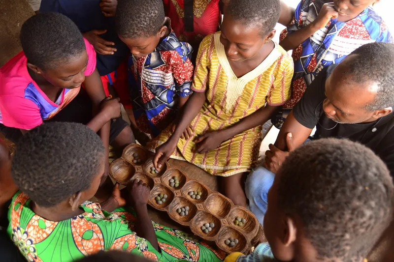 Trẻ em quây quần bên bàn Ayo bằng gỗ tại Nigeria.